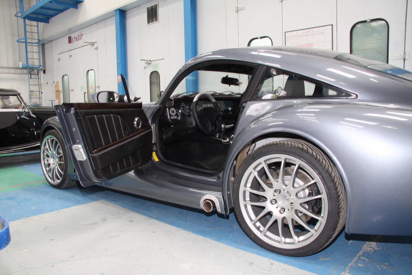 Grey Morgan AeroMax with its driver’s door open, showing the pleated door trim, dashboard dials and the side exhaust under the sill