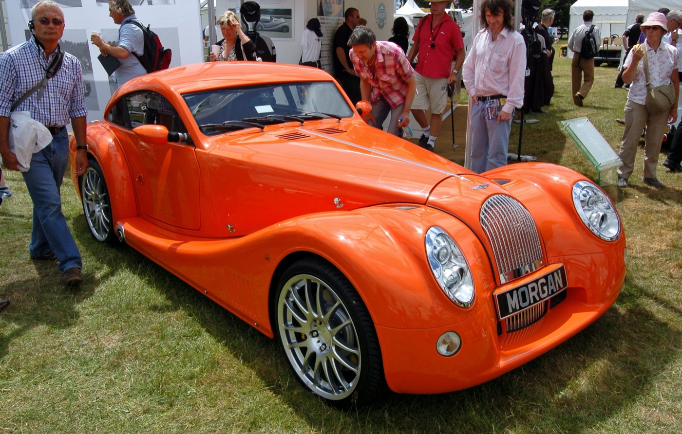 Orange Morgan AeroMax coupé on the grass at the Goodwood Festival of Speed, with visitors walking past