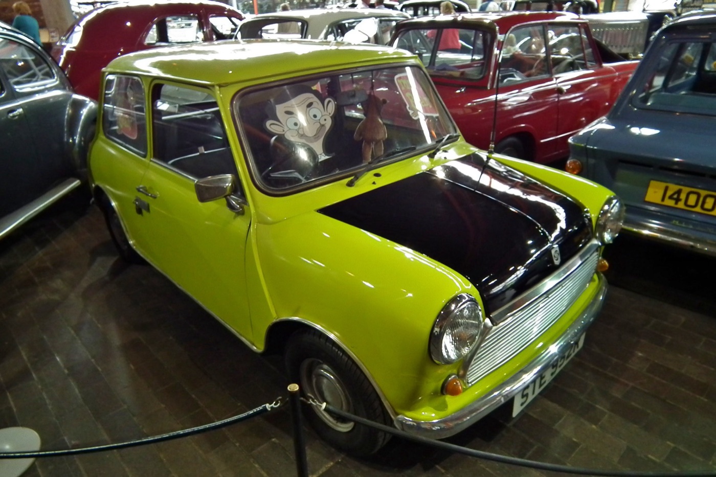 Citron Green Mini with a black bonnet and the plate STE 952R behind a rope, a cut-out of cartoon Mr. Bean in the driver