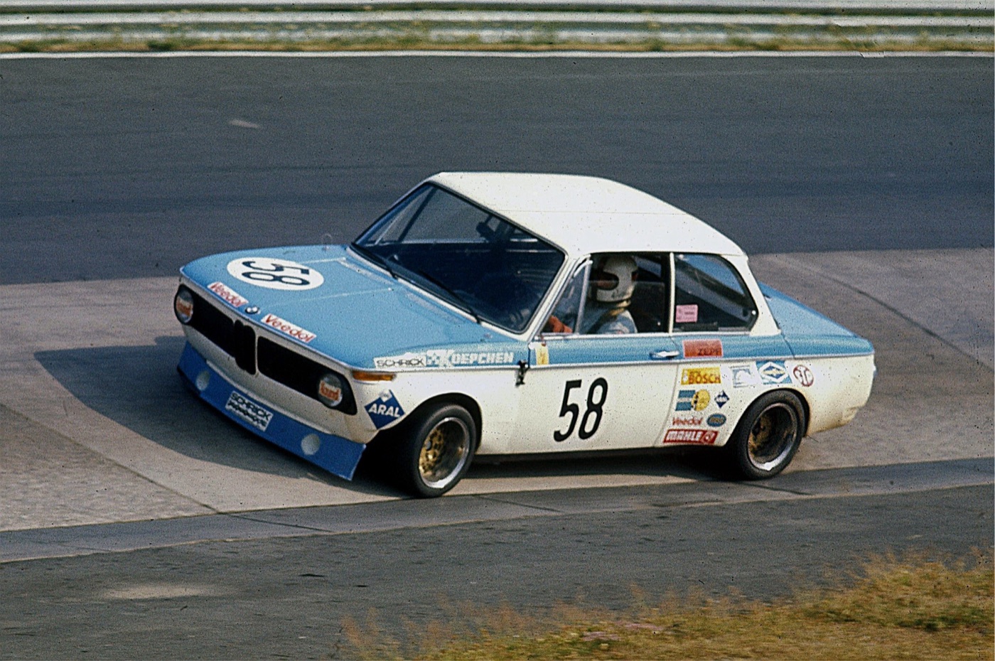 Blue and white BMW 2002 saloon number 58 with Koepchen and Schrick lettering cornering on the concrete banking of the Karussell