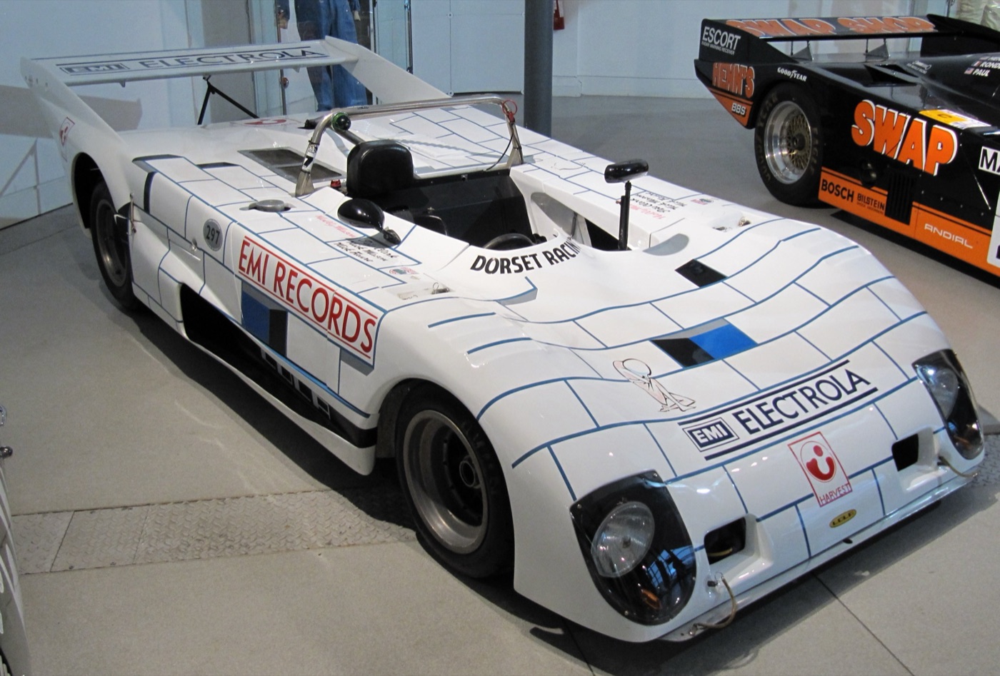 White Lola T297 open sports-prototype with a brick-pattern livery and EMI Records, EMI Electrola and Dorset Racing lettering, on display indoors