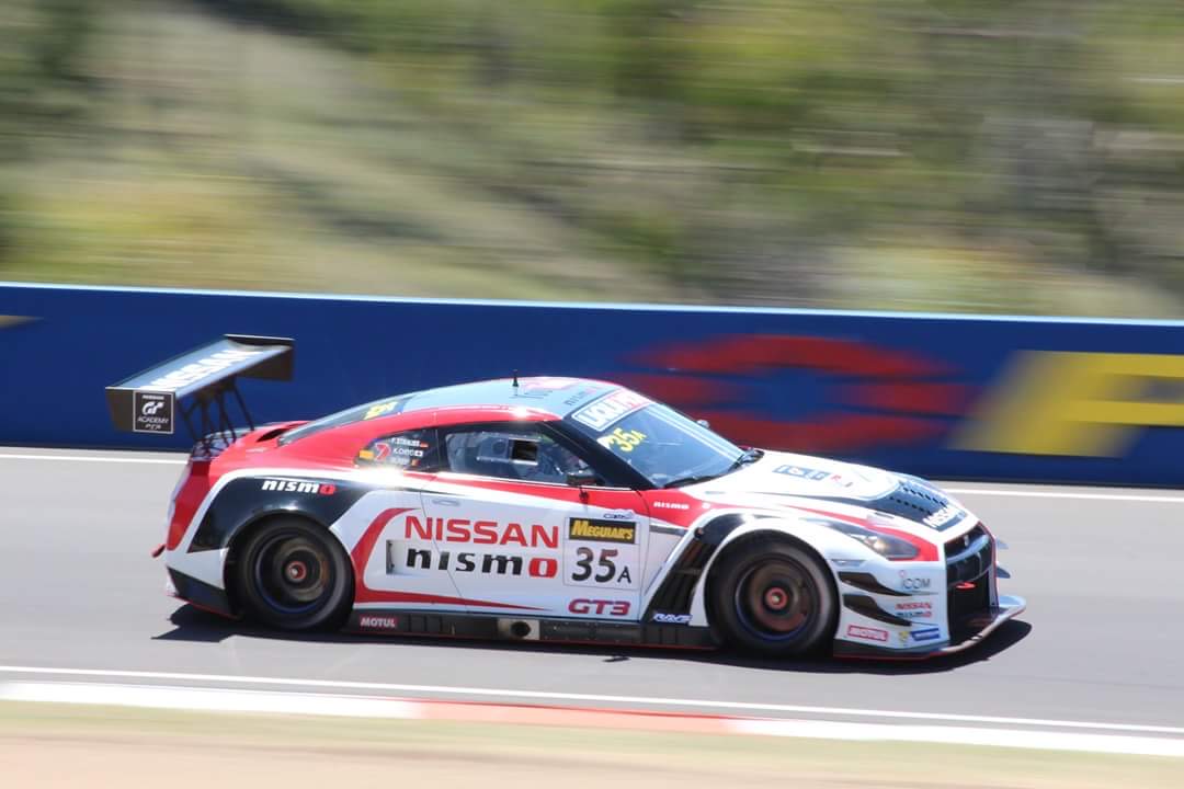 Red, white and black Nissan GT-R Nismo GT3 number 35 at speed past a blue wall at Mount Panorama