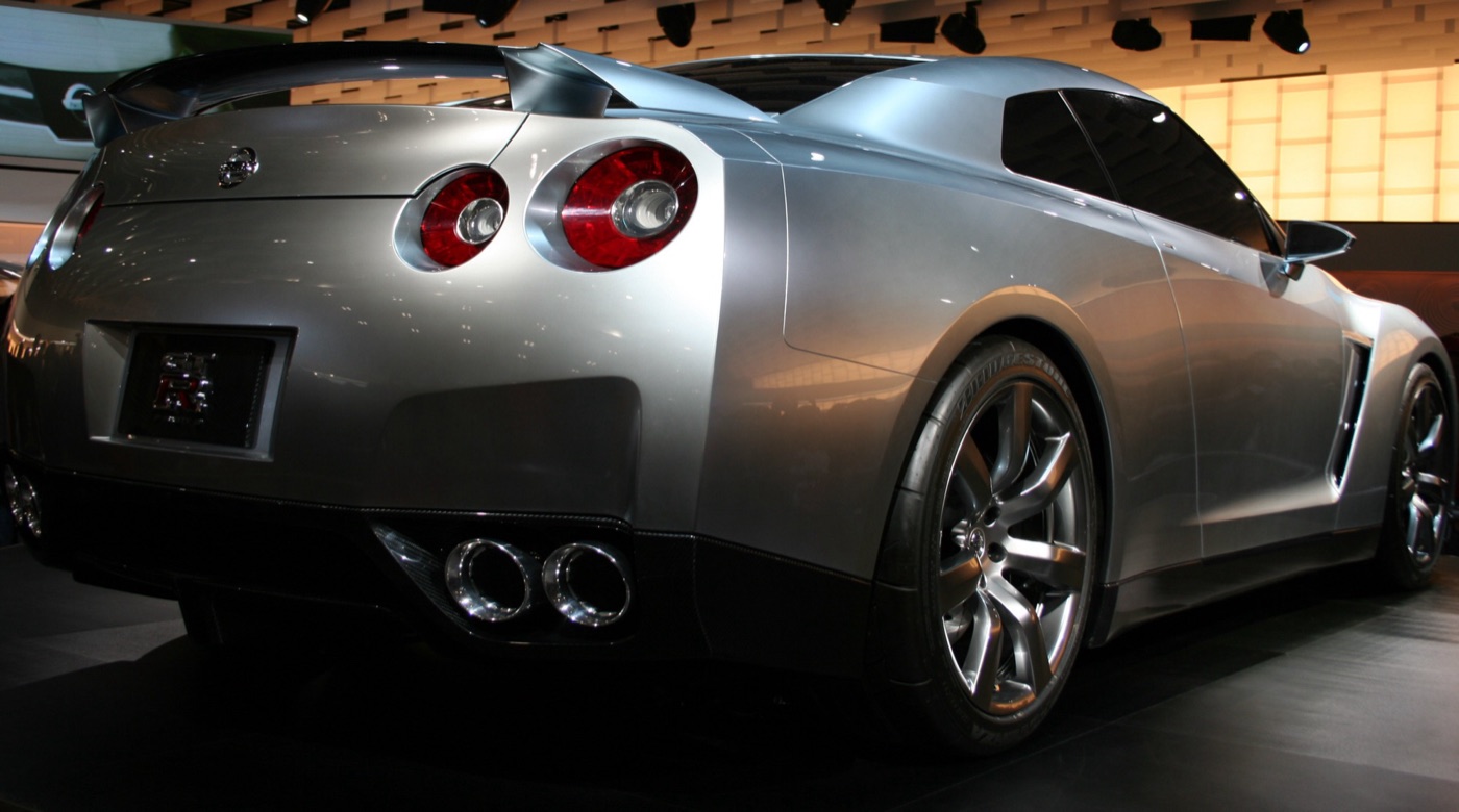 Rear three-quarter view of the silver Nissan GT-R Proto concept, with its four round tail lights and quad exhausts, on a show stand