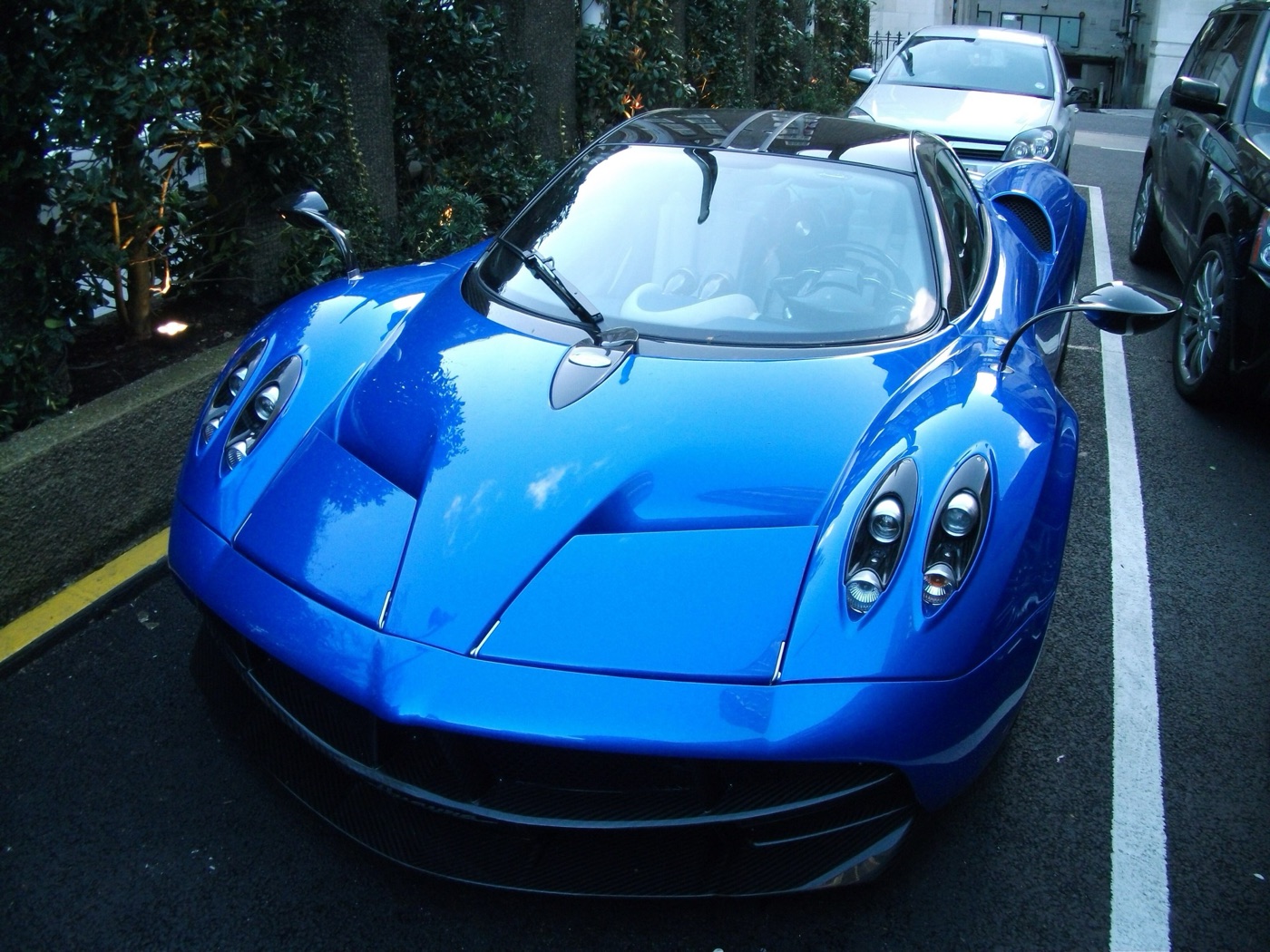 Blue Pagani Huayra coupé seen from the front, showing its quad headlamps, bonnet scoop and leaf-shaped mirrors