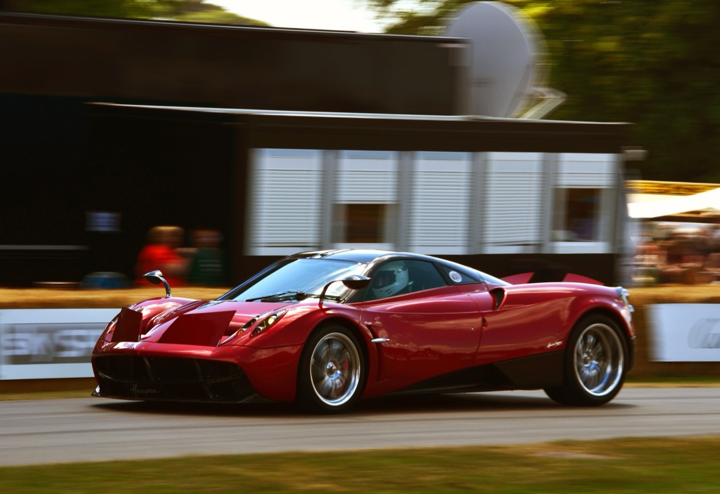 Red Pagani Huayra driving up the Goodwood hill with its front and rear active flaps raised