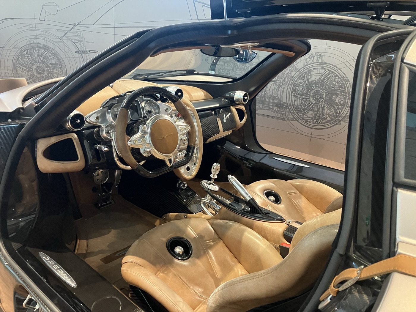 Interior of a Pagani Huayra with tan leather seats, a carbon and aluminium steering wheel and the exposed gear linkage