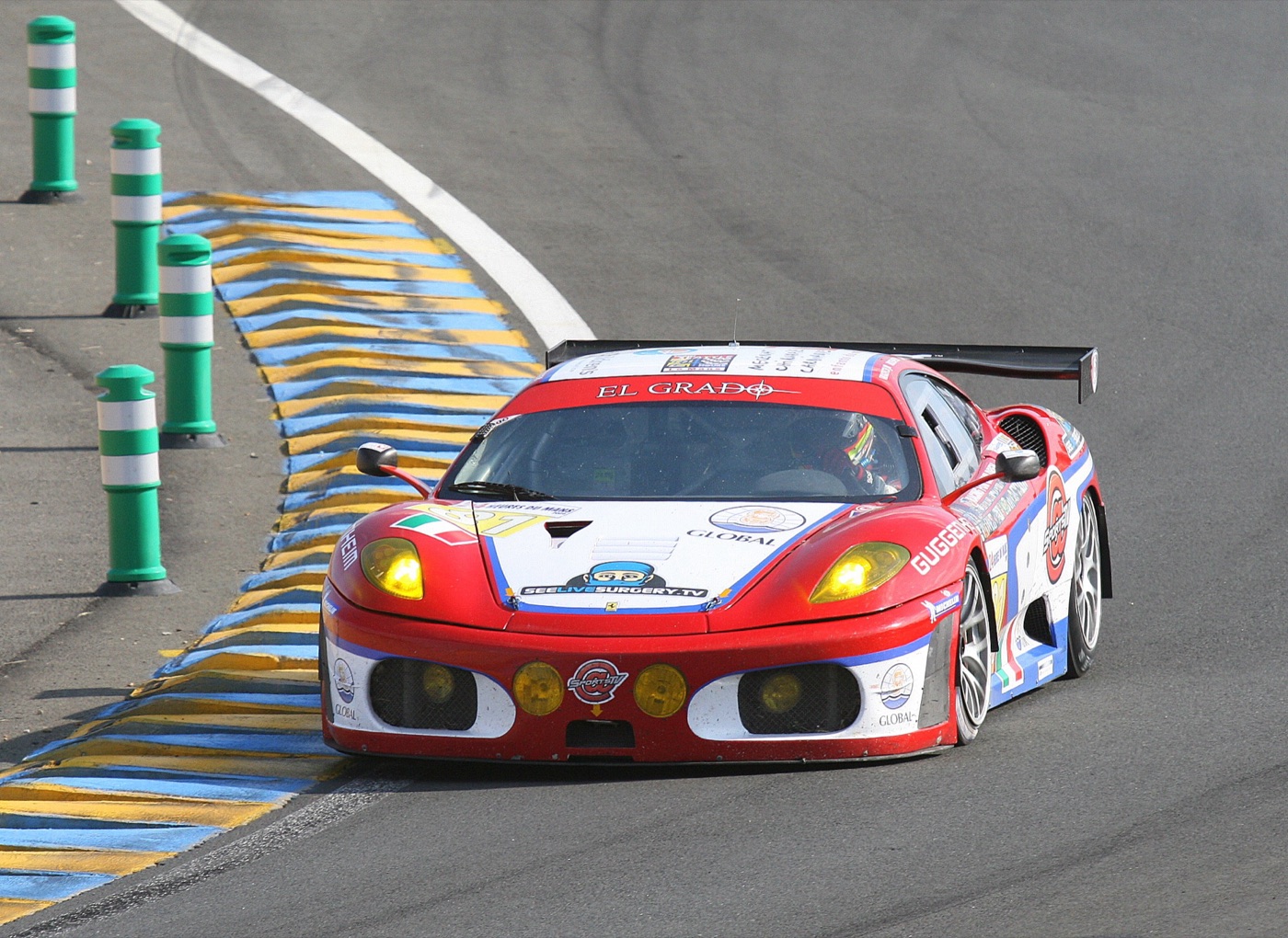 A red, white and blue Ferrari F430 GT2 on the kerbs of the Esses at Le Mans