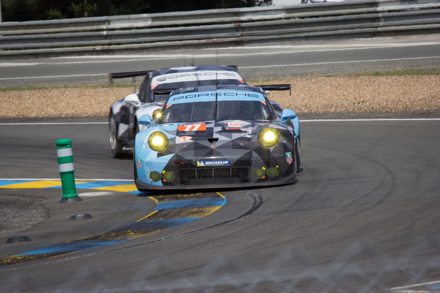 The blue and grey No. 77 Dempsey-Proton Racing Porsche 911 RSR leading another 911 through a corner at Le Mans