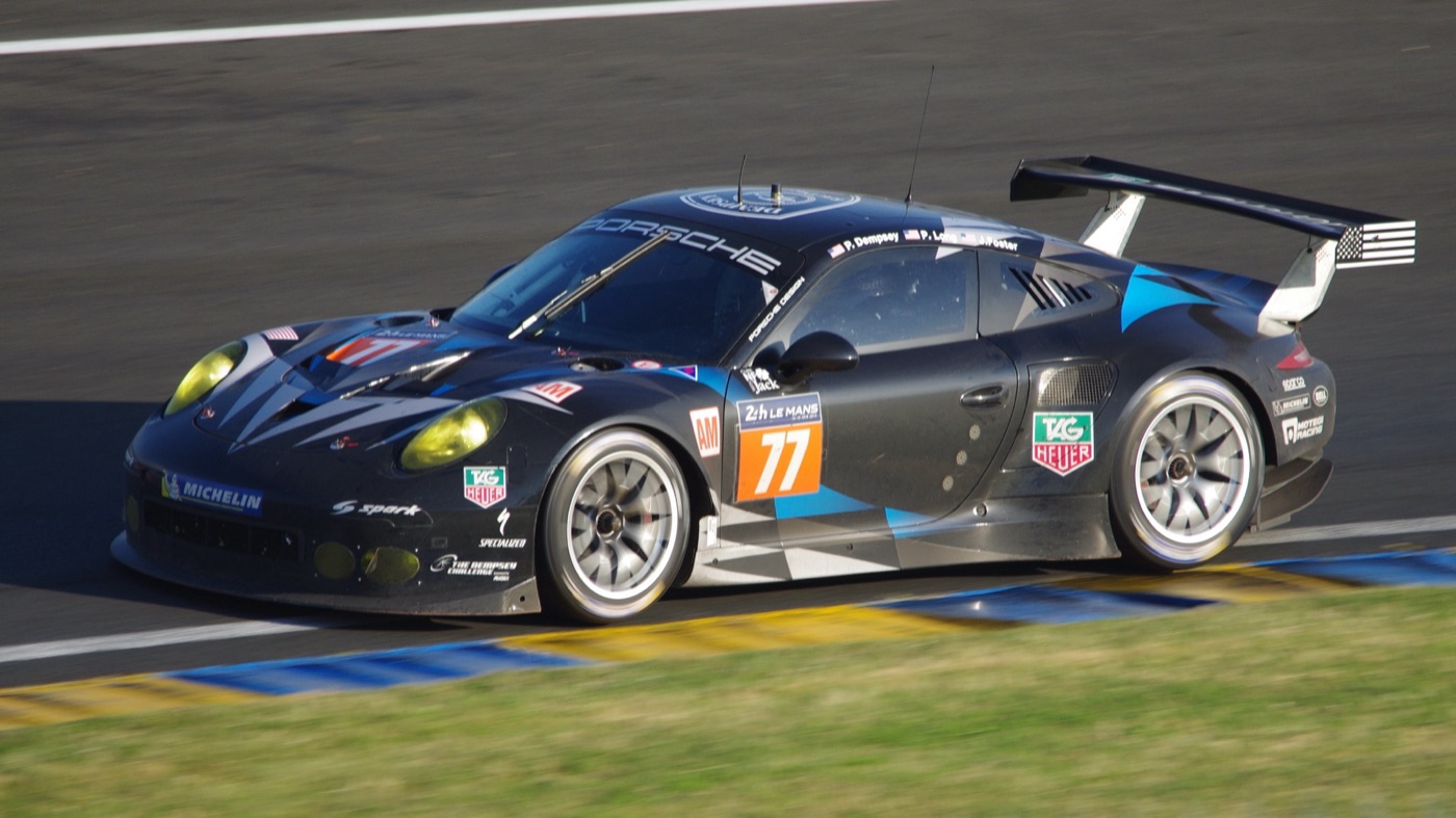 The black and blue No. 77 Dempsey Racing-Proton Porsche 911 RSR at speed in the Esses at Le Mans