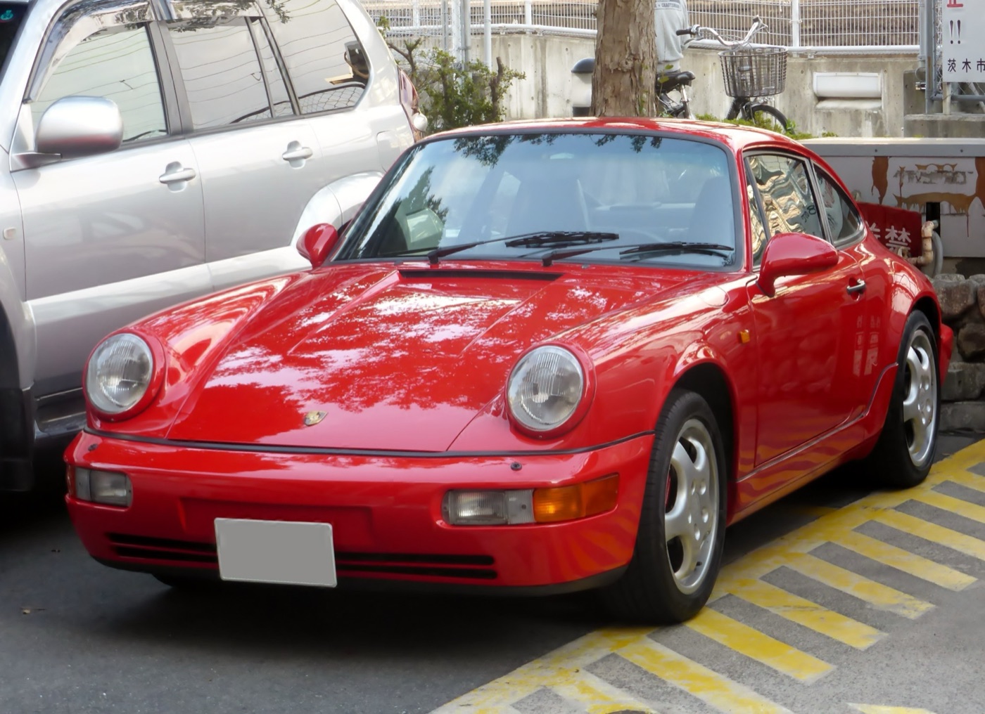 Red Porsche 964 Carrera 2 coupé seen from the front, with its smooth moulded bumpers