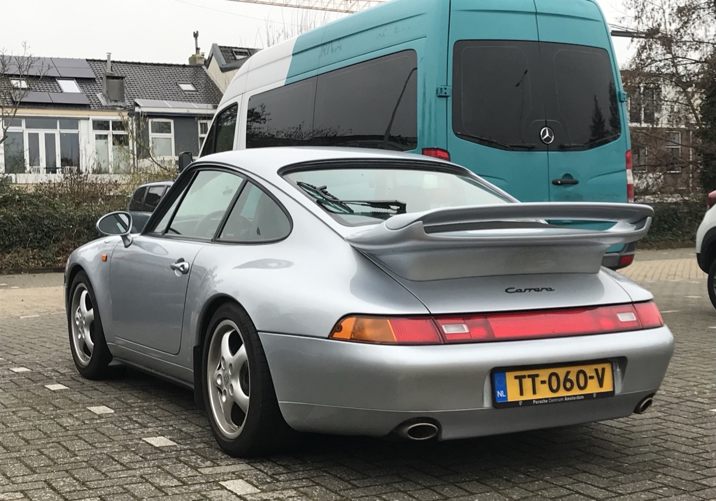Silver 1995 Porsche 911 Carrera (993) coupé from the rear three-quarters, with a fixed rear wing