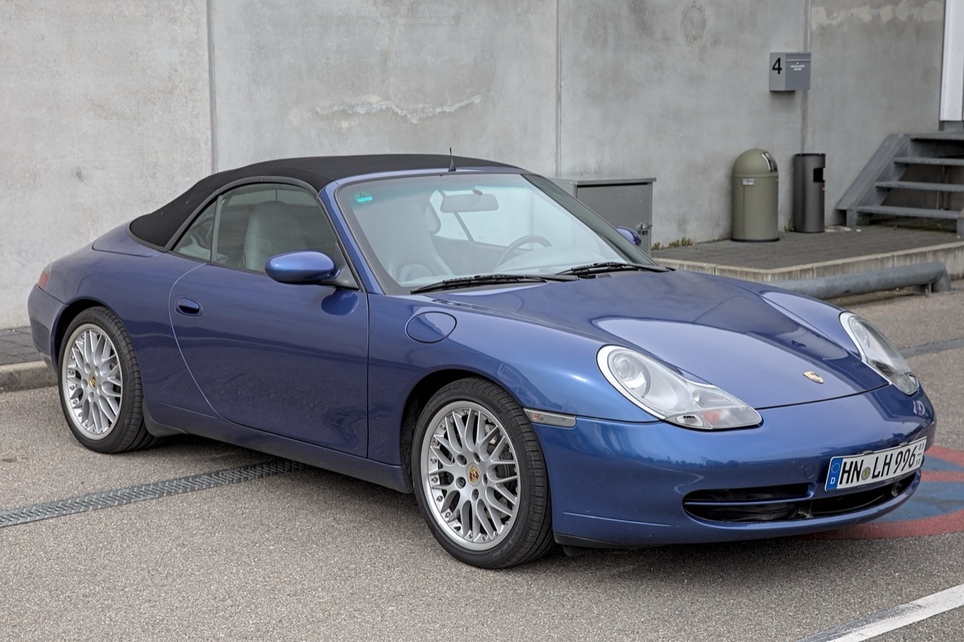 Blue first-series Porsche 996 Carrera Cabriolet with the hood up, showing its teardrop headlamps