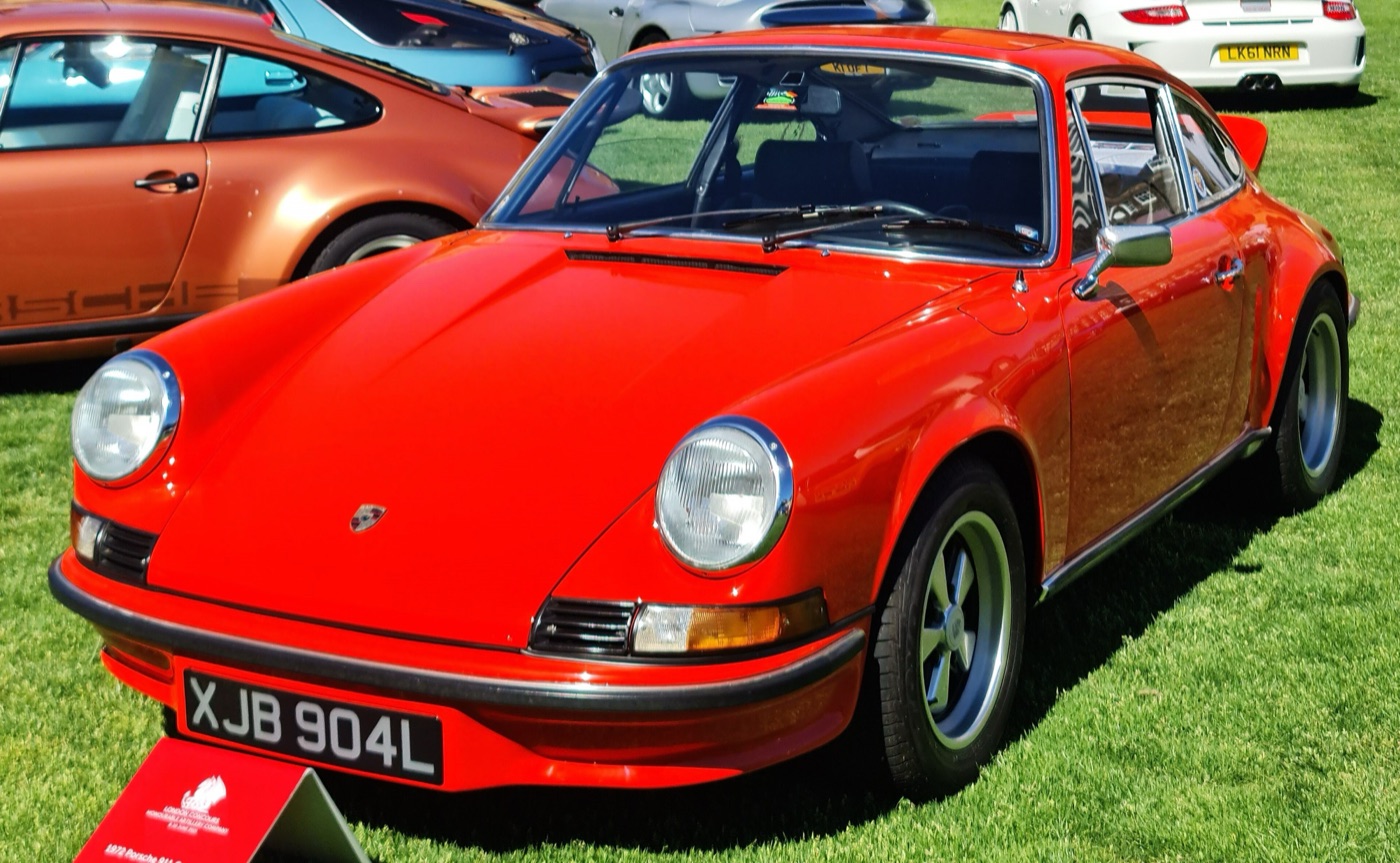 Orange 1972 Porsche 911 Carrera RS 2.7 with its ducktail spoiler on the grass at a concours