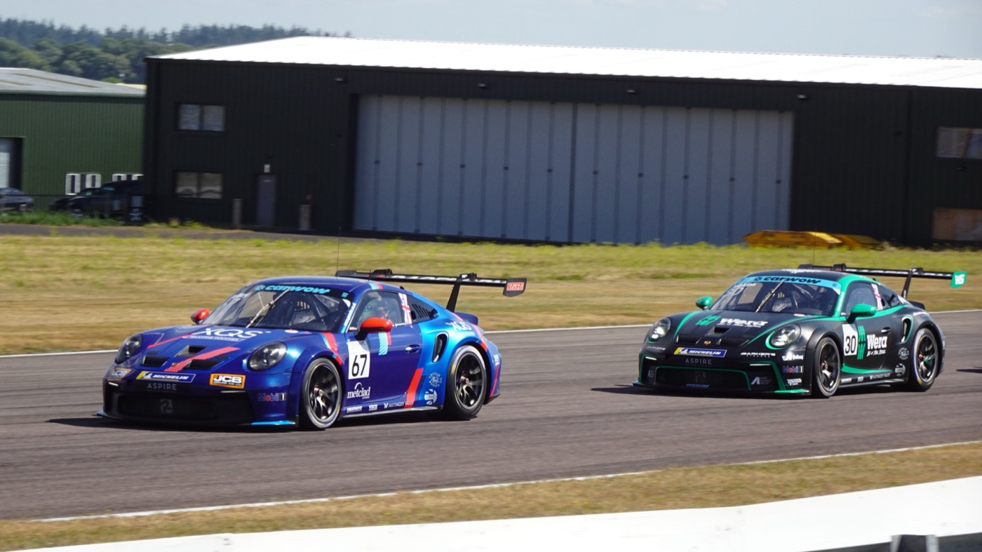 Blue Porsche 911 GT3 Cup number 67 ahead of a black and green 911 GT3 Cup number 30 at Thruxton