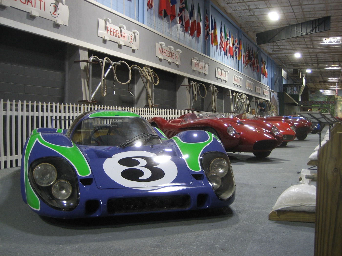Blue Porsche 917 long-tail with green swirls and number 3 in a museum garage display