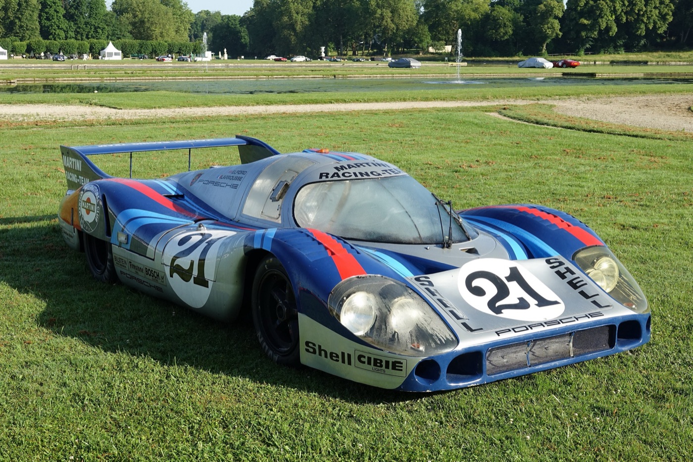 Martini-liveried Porsche 917 long-tail number 21 with covered rear wheels parked on grass