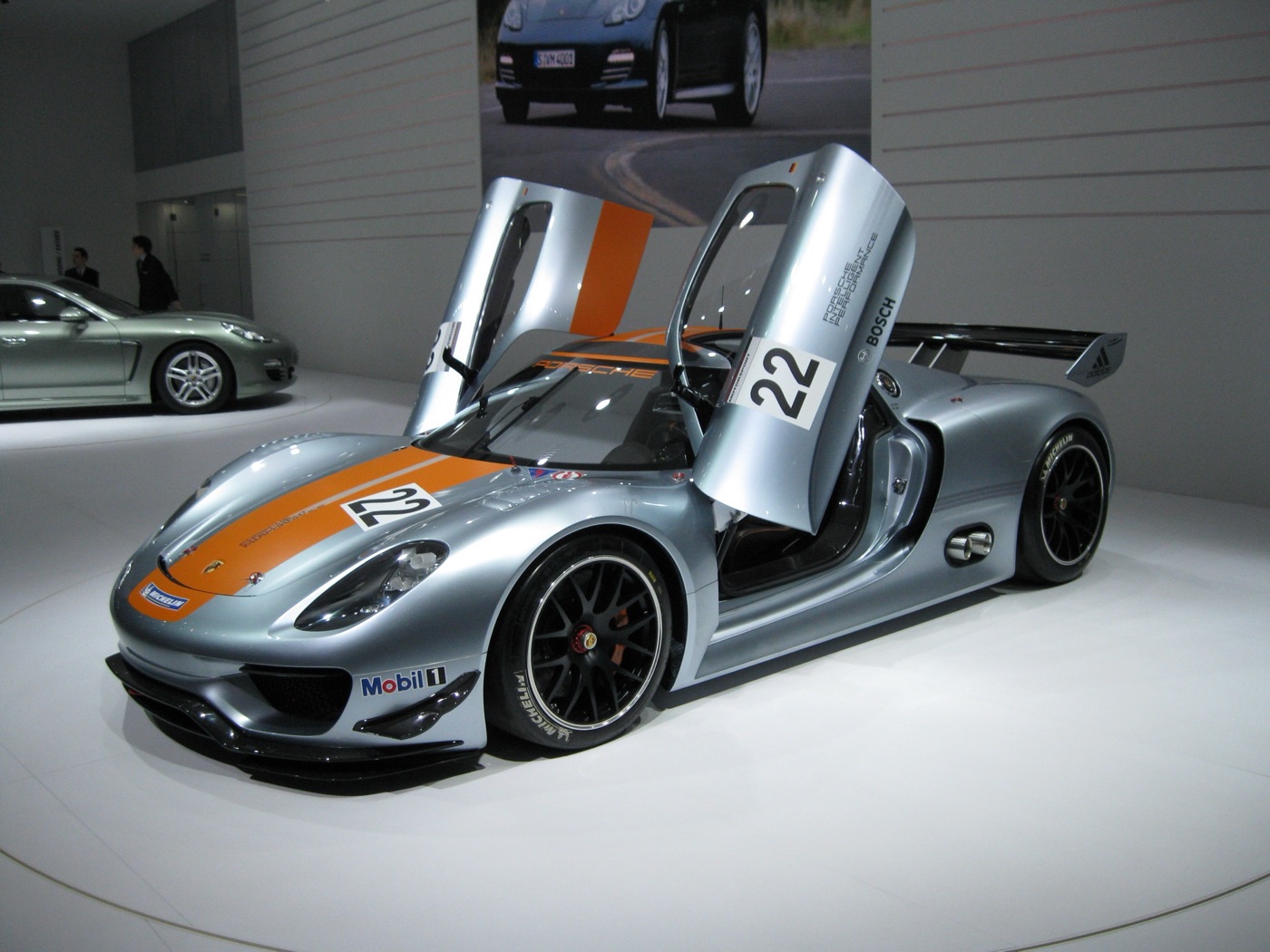Silver Porsche 918 RSR coupé with orange stripes, number 22 and both butterfly doors raised