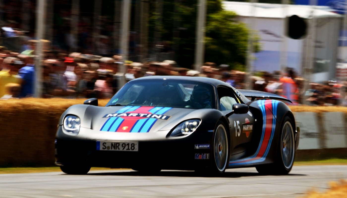 Black Porsche 918 Spyder in Martini stripes with number 15 driving past straw bales and spectators