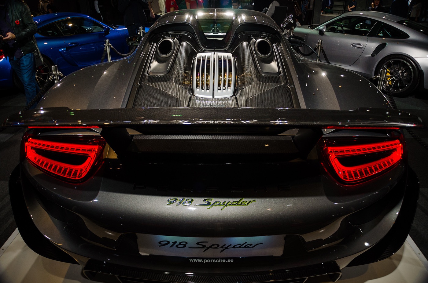 Rear view of a grey Porsche 918 Spyder showing the two exhaust outlets on top of the engine cover, the rear wing and the 918 Spyder script