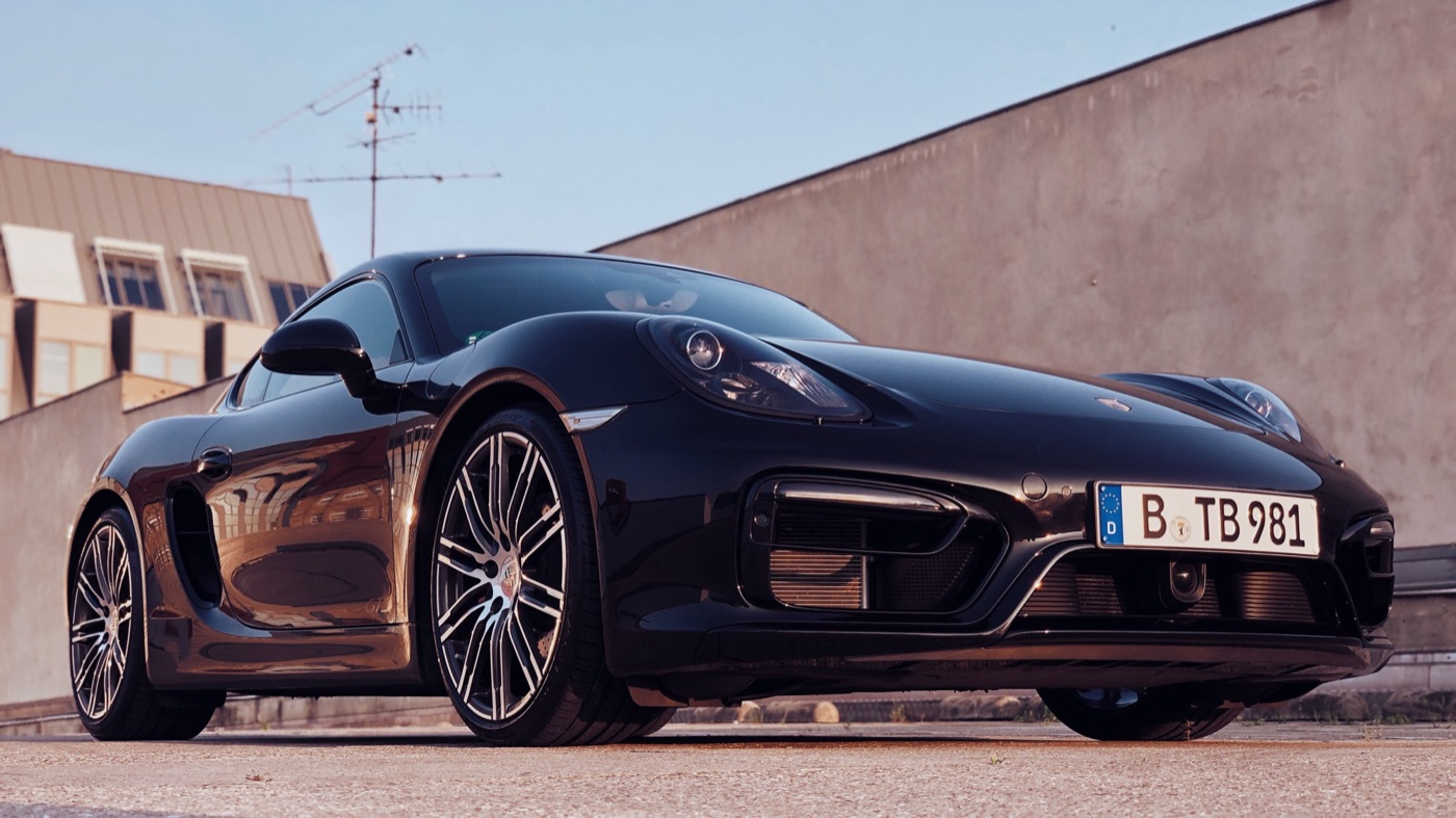 Black Porsche Cayman GTS of the 981 series with two-tone 20-inch wheels and a Berlin number plate, photographed low from the front