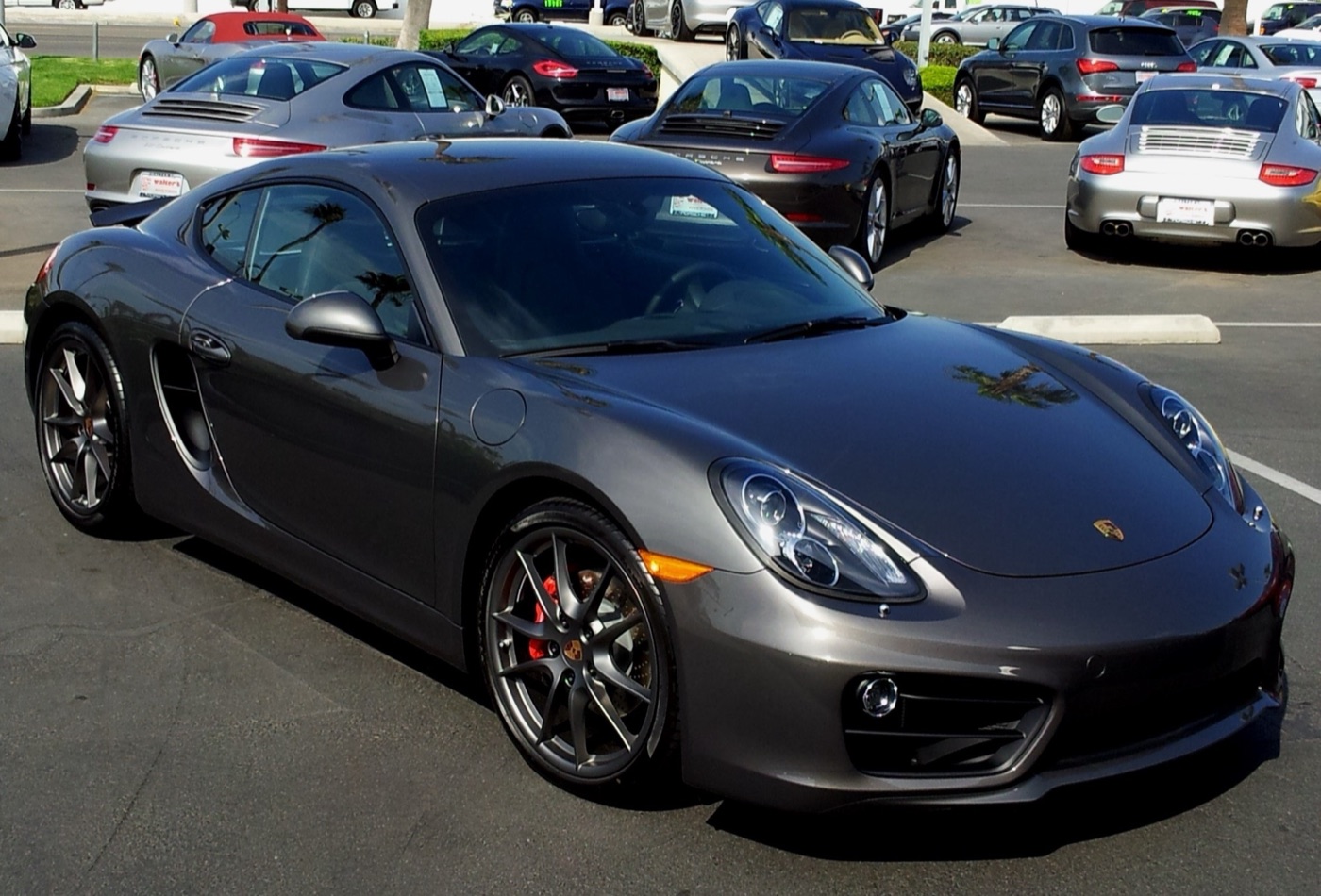 Agate grey 2014 Porsche Cayman S of the 981 series with graphite 20-inch wheels, parked in front of other Porsches