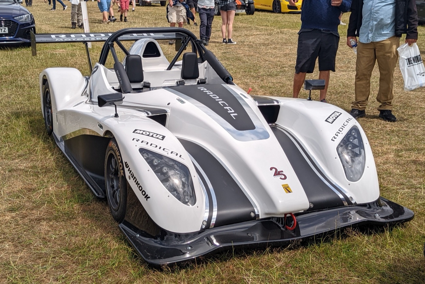 White Radical SR1 XXR with black stripes and Hankook decals parked on grass at an outdoor show