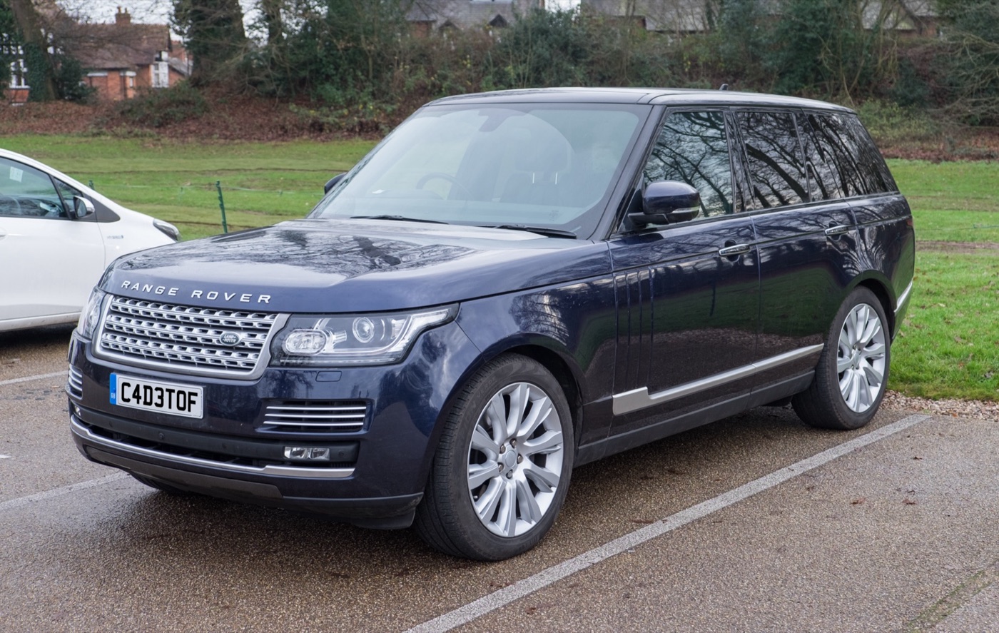 Dark blue pre-facelift Range Rover Autobiography with silver wheels parked in a car park beside grass, front three-quarter view
