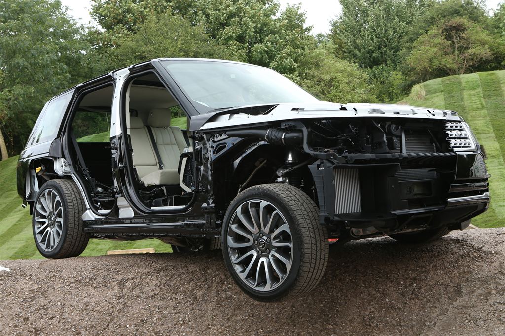 Sectioned black fourth-generation Range Rover with its front panels and doors cut away to show the silver aluminium body structure, radiators and front suspension