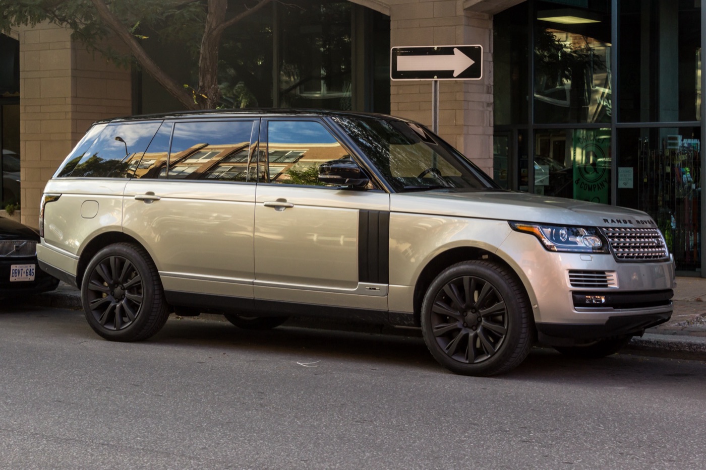 Silver long-wheelbase fourth-generation Range Rover with a black roof and dark wheels parked at a city kerb, front three-quarter view