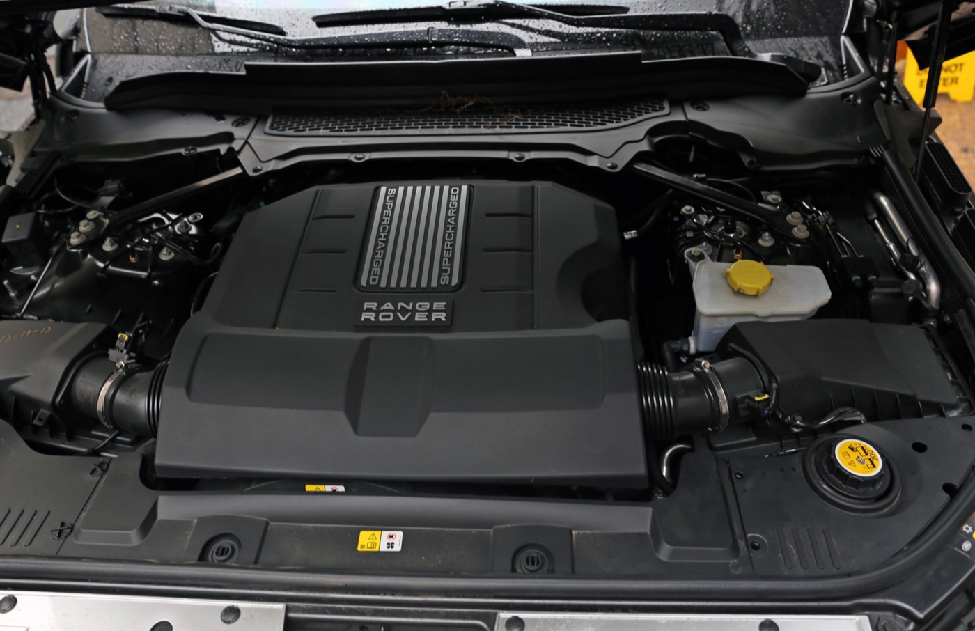 Engine bay of a fourth-generation Range Rover showing the black Range Rover engine cover over the supercharged 5.0-litre V8