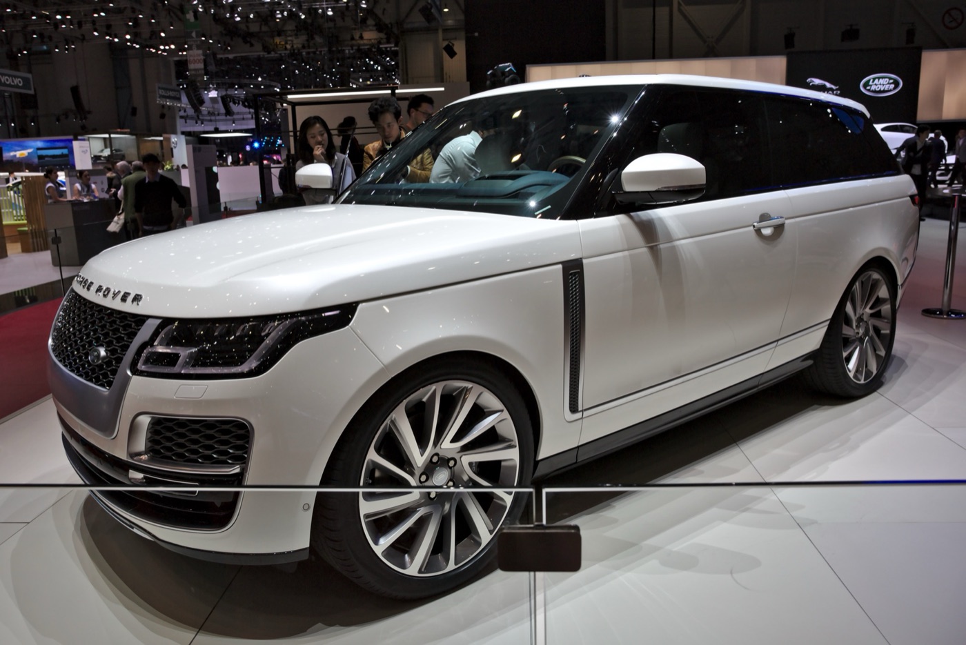 White two-door Range Rover SV Coupé with large multi-spoke wheels on a motor show stand