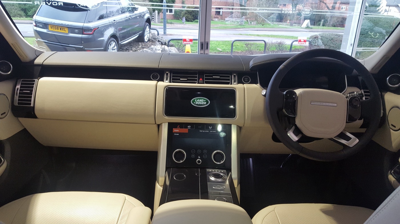 Cream leather dashboard of a facelifted Range Rover Vogue with two stacked centre touchscreens and a right-hand-drive steering wheel