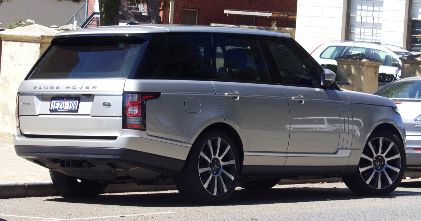 Silver pre-facelift Range Rover Vogue parked on a street, rear three-quarter view showing the split tailgate and vertical tail lamps