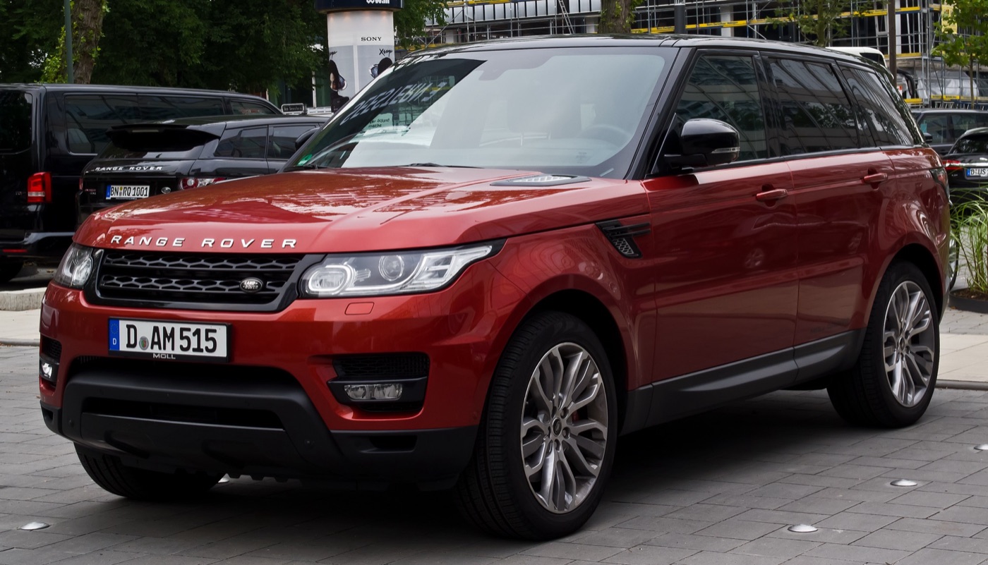 Red Range Rover Sport L494 SDV6 HSE with a black roof, parked on a paved square, seen from the front three-quarter
