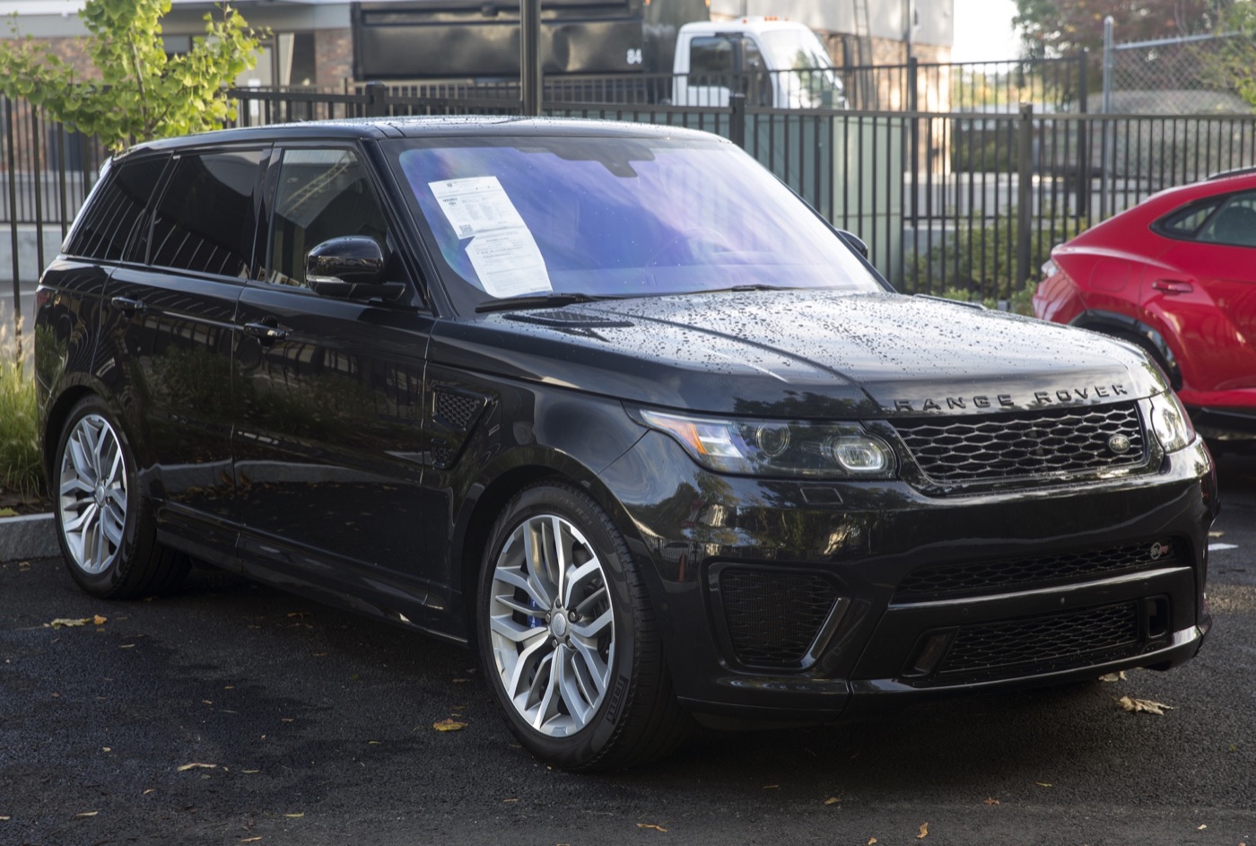 Black 2016 Range Rover Sport SVR with silver twin-spoke wheels and blue brake callipers on a dealer forecourt