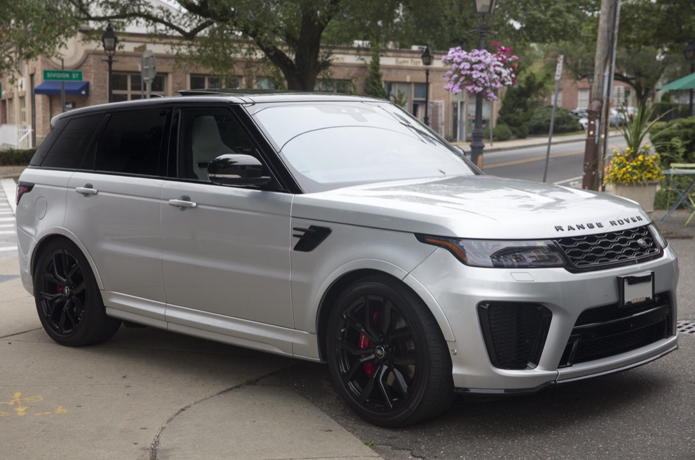 Silver facelifted Range Rover Sport SVR with a black roof, black wheels and red brake callipers parked on a street corner