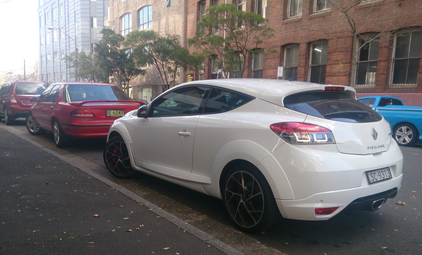White Megane Renaultsport 250 coupé with dark 19-inch wheels and red brake calipers parked on a city street