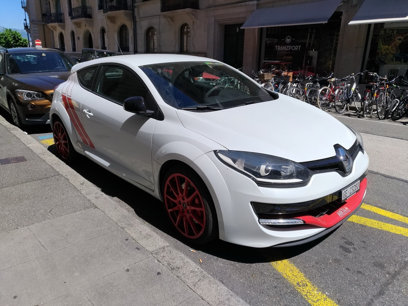 White Megane RS 275 Trophy-R with red wheels and red stripes parked at a Geneva kerb
