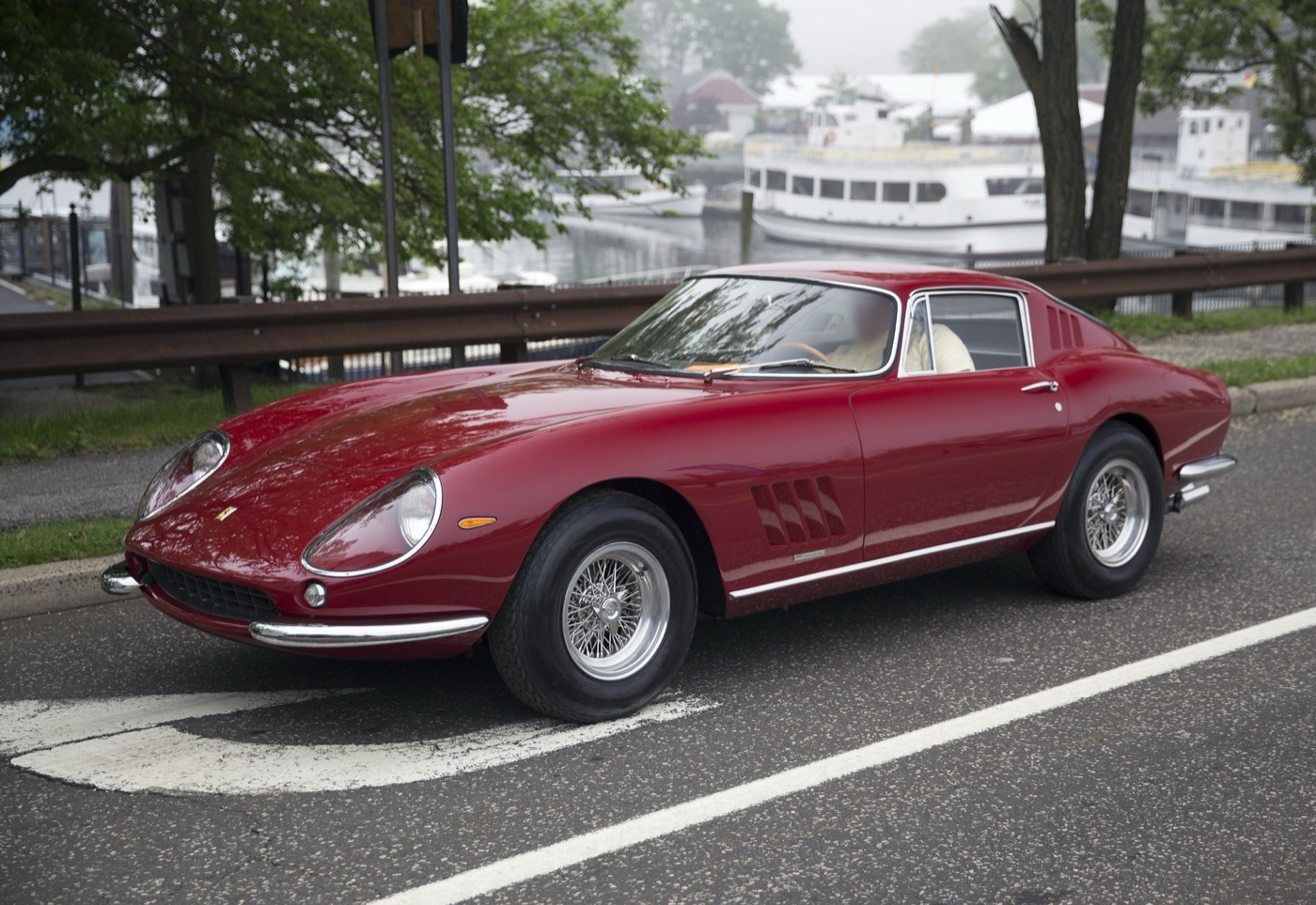 Dark red 1966 Ferrari 275 GTB coupé with wire wheels, parked by a harbour