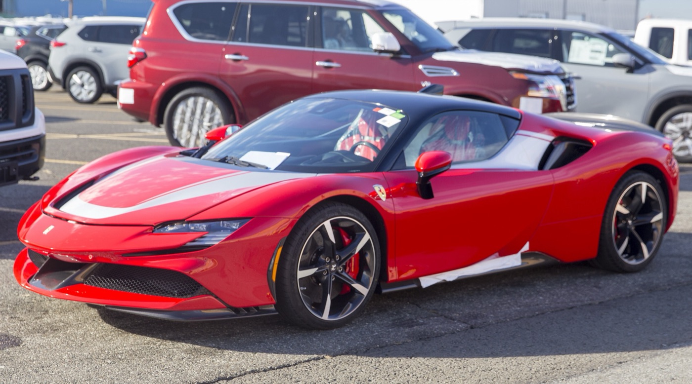 Red 2022 Ferrari SF90 Stradale with a white bonnet stripe and black wheels, parked in a vehicle compound