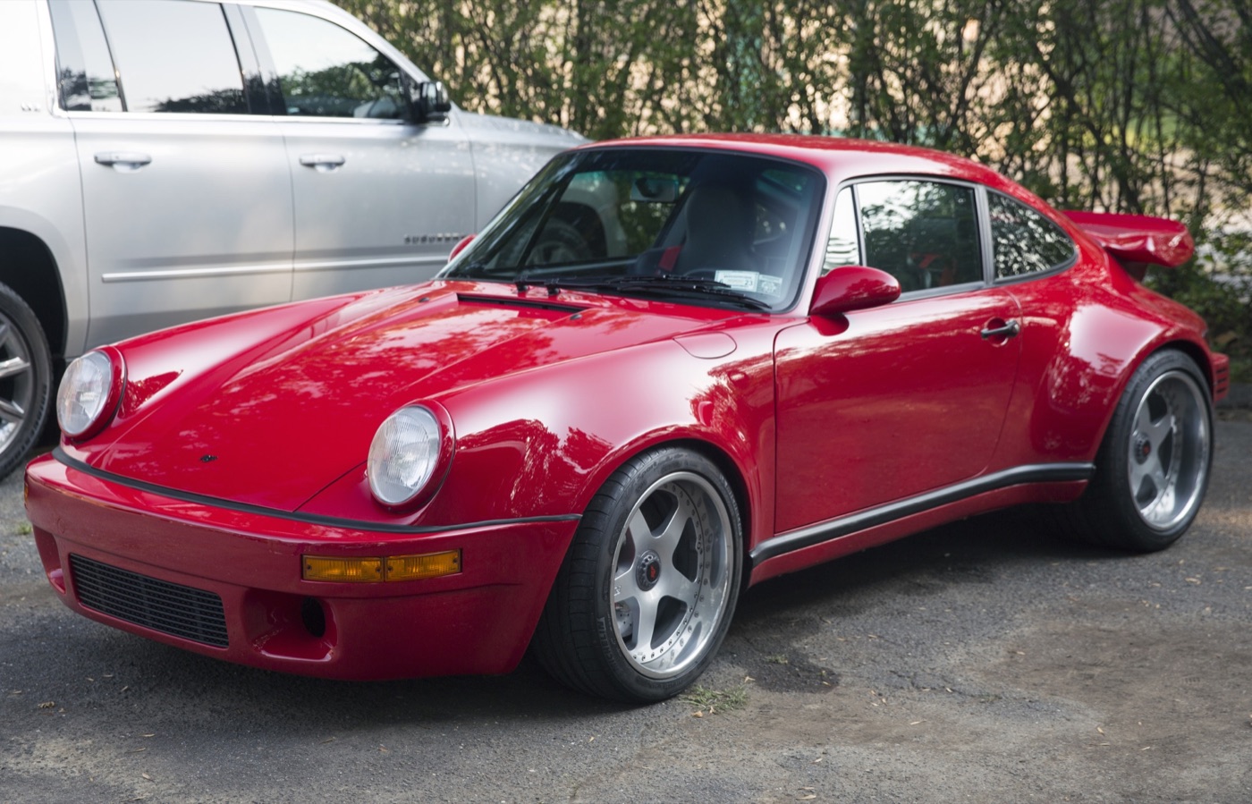 Red Ruf CTR with five-spoke wheels and a rear wing parked beside a silver SUV