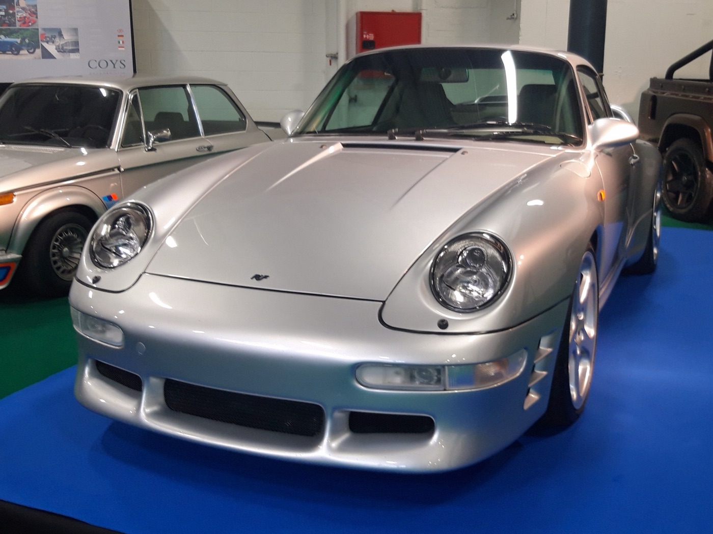 Silver Ruf CTR2 coupé based on the 993 911, seen from the front on a blue display carpet