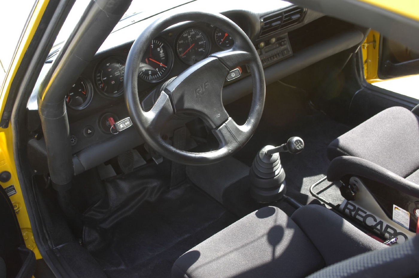Cabin of a Ruf CTR with a Ruf steering wheel, roll cage tube, gear lever and Recaro seat
