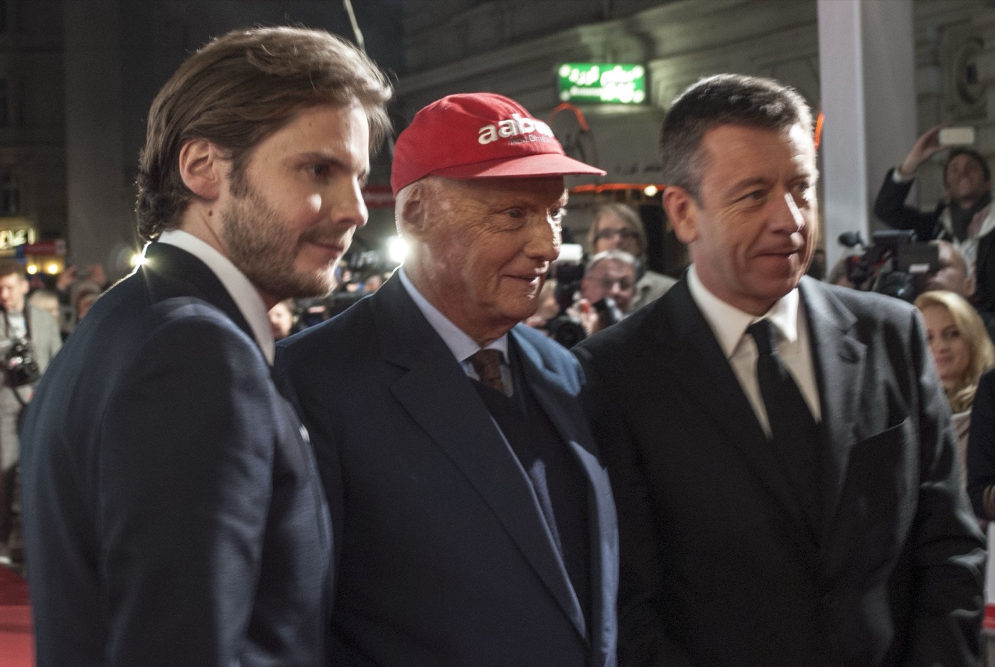 Daniel Brühl, Niki Lauda in his red cap and Peter Morgan on the red carpet at the Vienna premiere of Rush