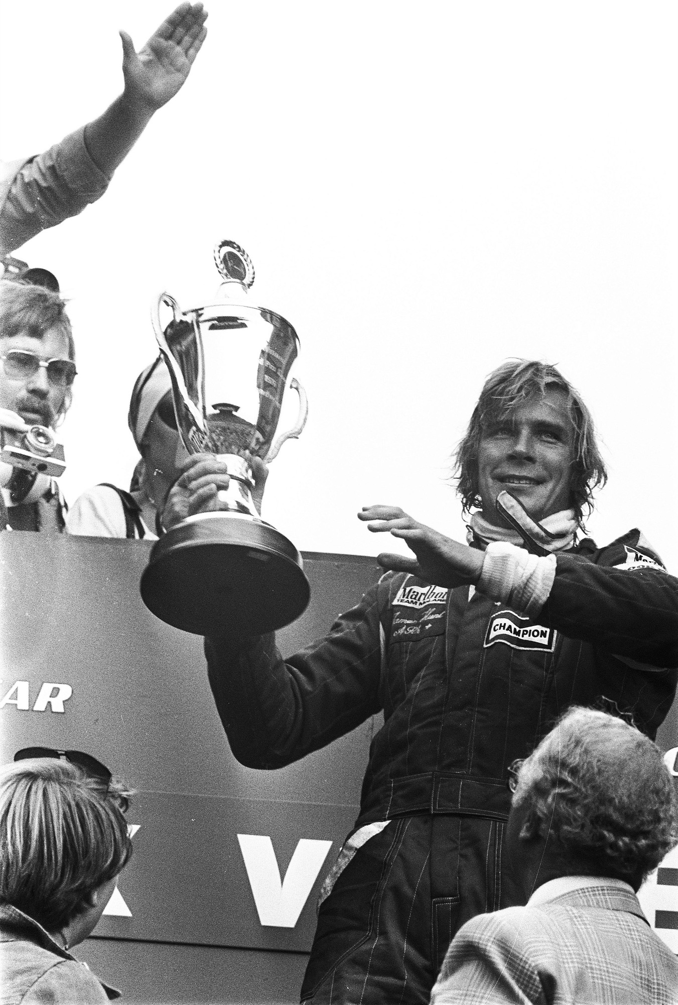 James Hunt in Marlboro McLaren overalls holding a large trophy on the podium
