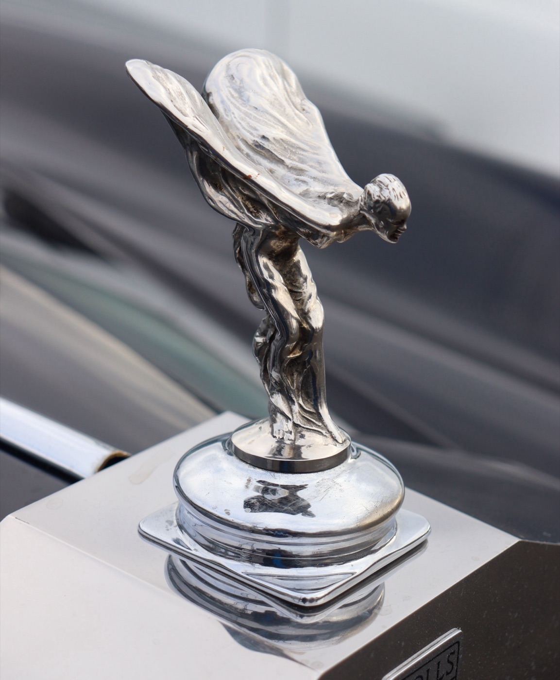 The Spirit of Ecstasy leaning forward with her robes spread behind her, on the radiator cap of a Rolls-Royce Silver Cloud I