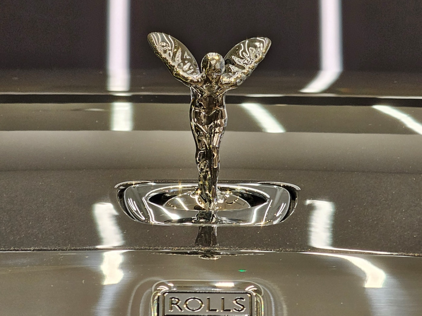The lower Spectre version of the Spirit of Ecstasy, seen head-on above the Rolls-Royce lettering on an anthracite bonnet