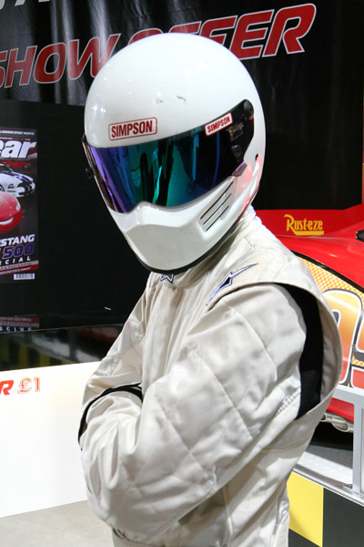 The Stig in a white racing suit and white Simpson helmet with a mirrored visor
