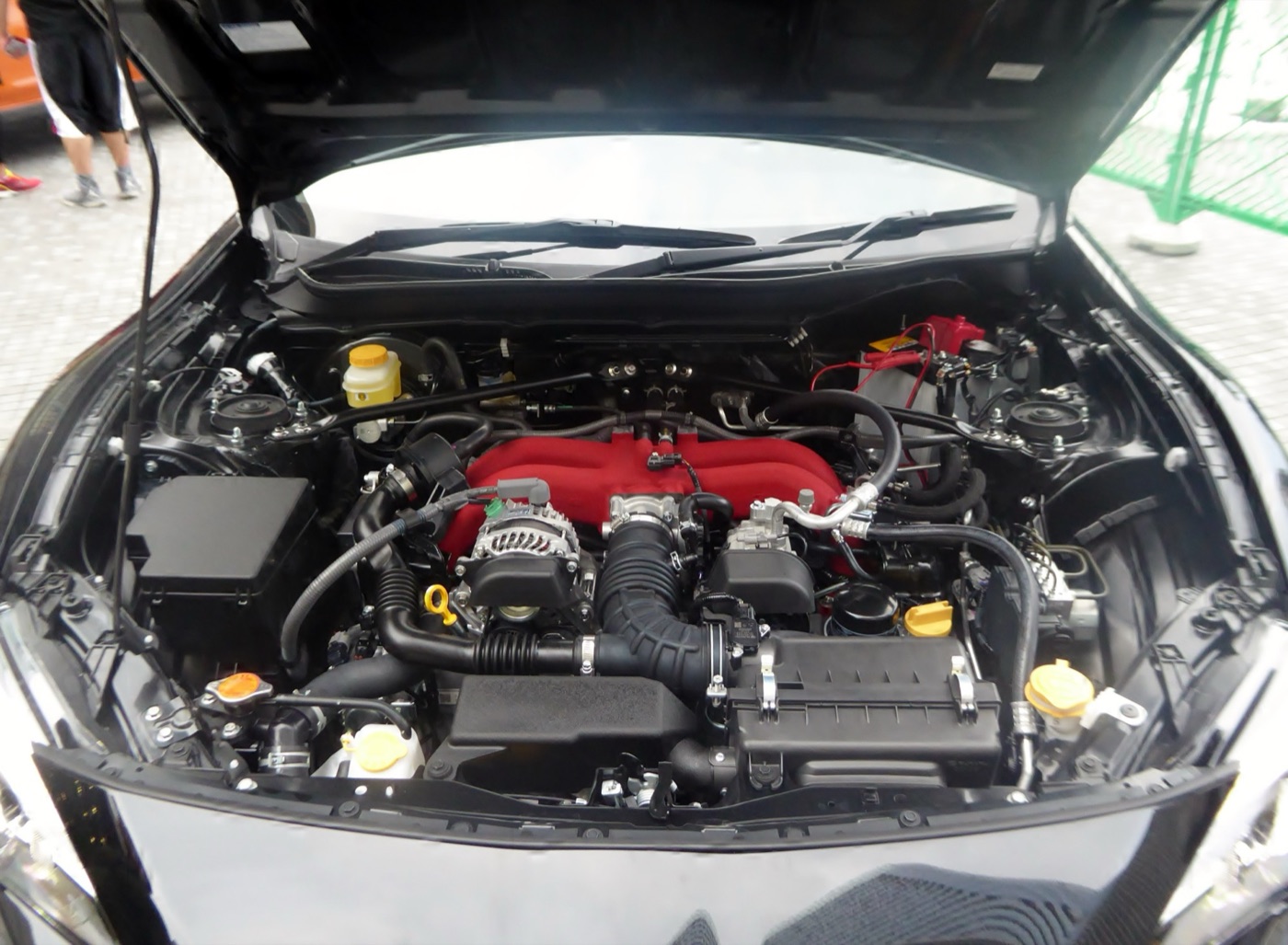 Engine bay of a black Subaru BRZ showing the flat FA20 boxer engine with its red intake manifold