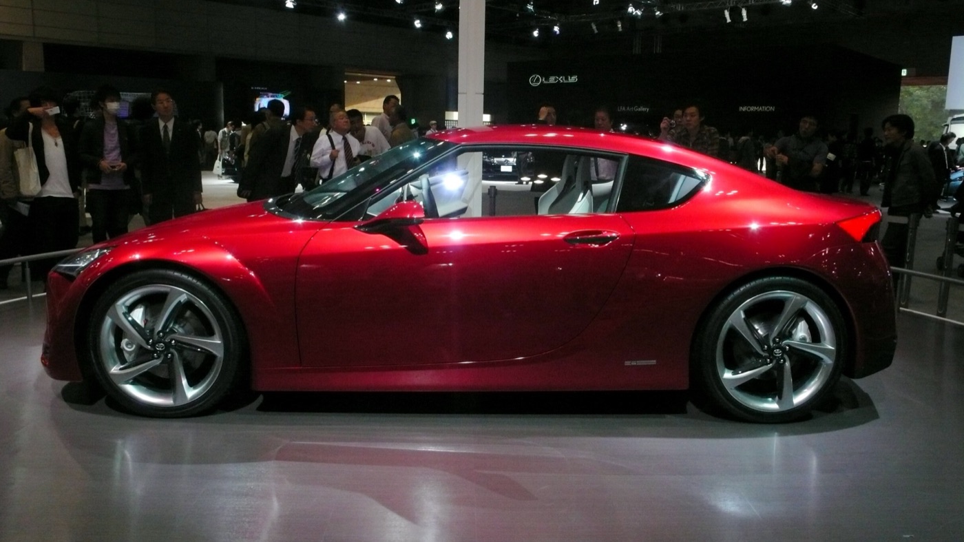 Red Toyota FT-86 Concept coupe in side view on the Toyota stand, with show visitors behind it